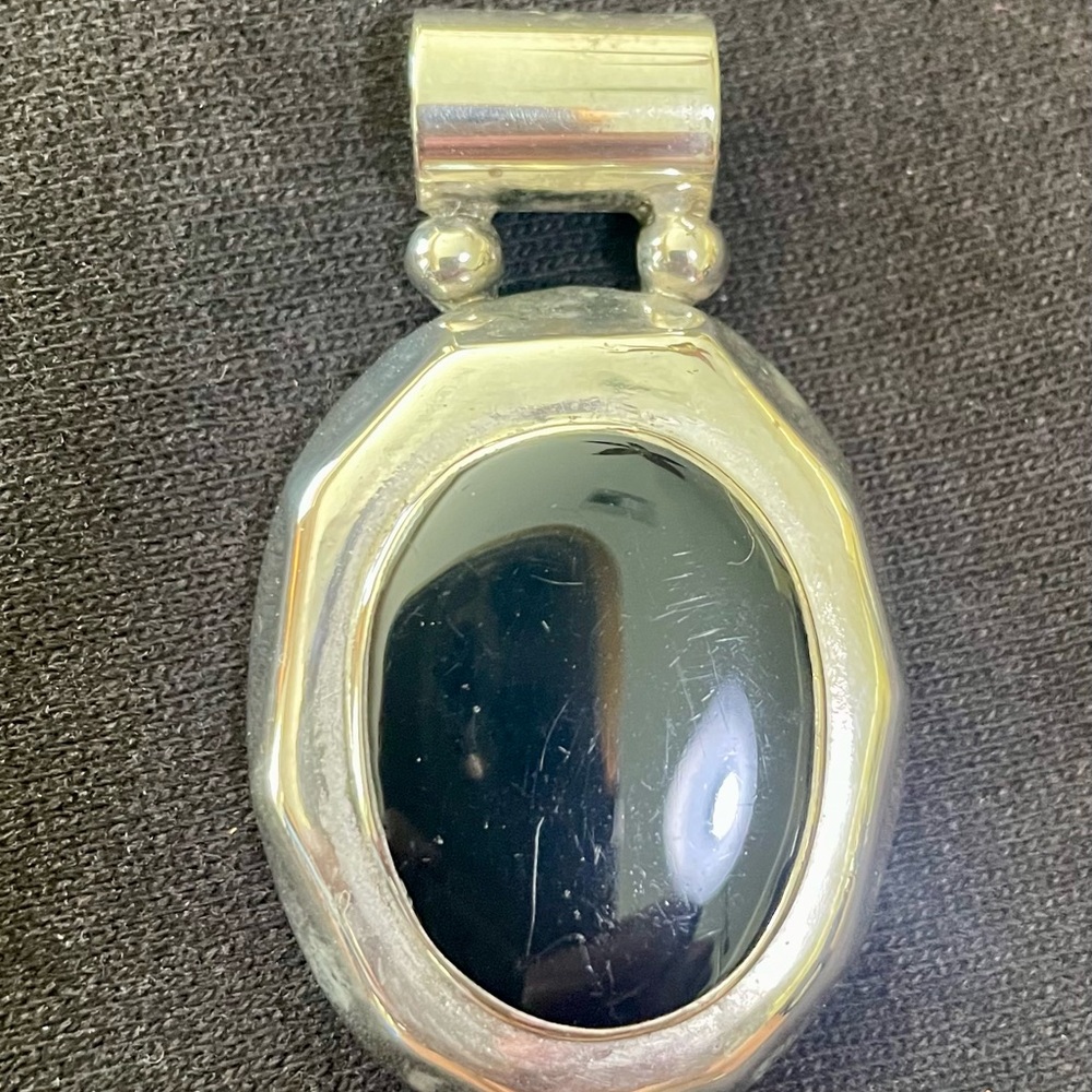 Sterling silver pendant with Black stone in the center. Slightly used